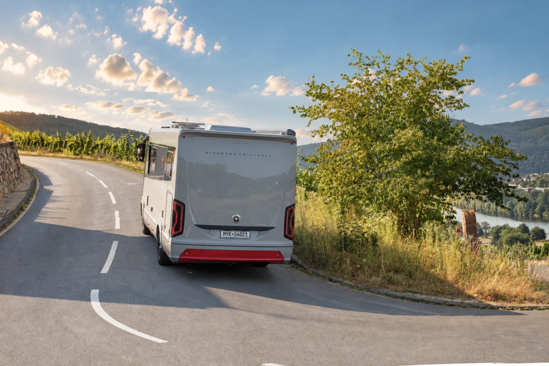 iSmove 2027 vu de l’arrière sur une route bordée de vignes, avec vue sur une vallée