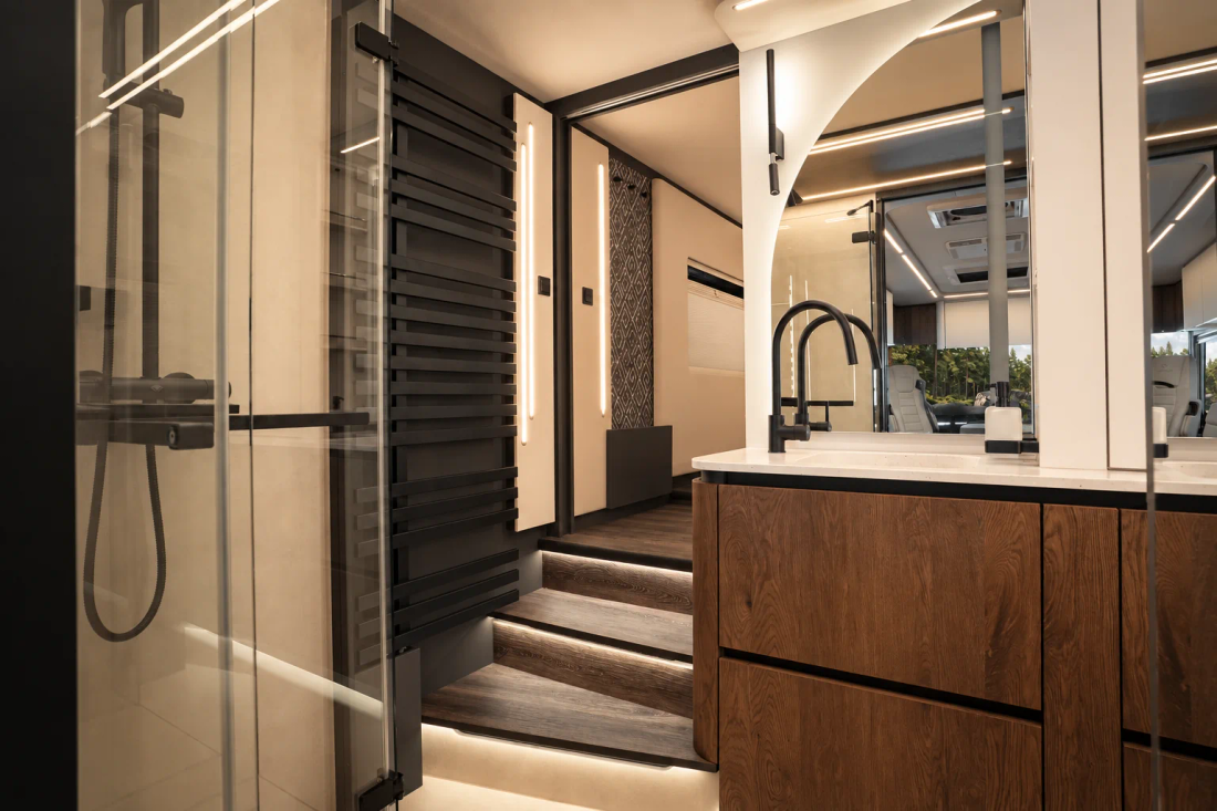 Salle de bains du Concorde Centurion 2027 avec douche vitrée, robinet noir et meuble vasque en bois
