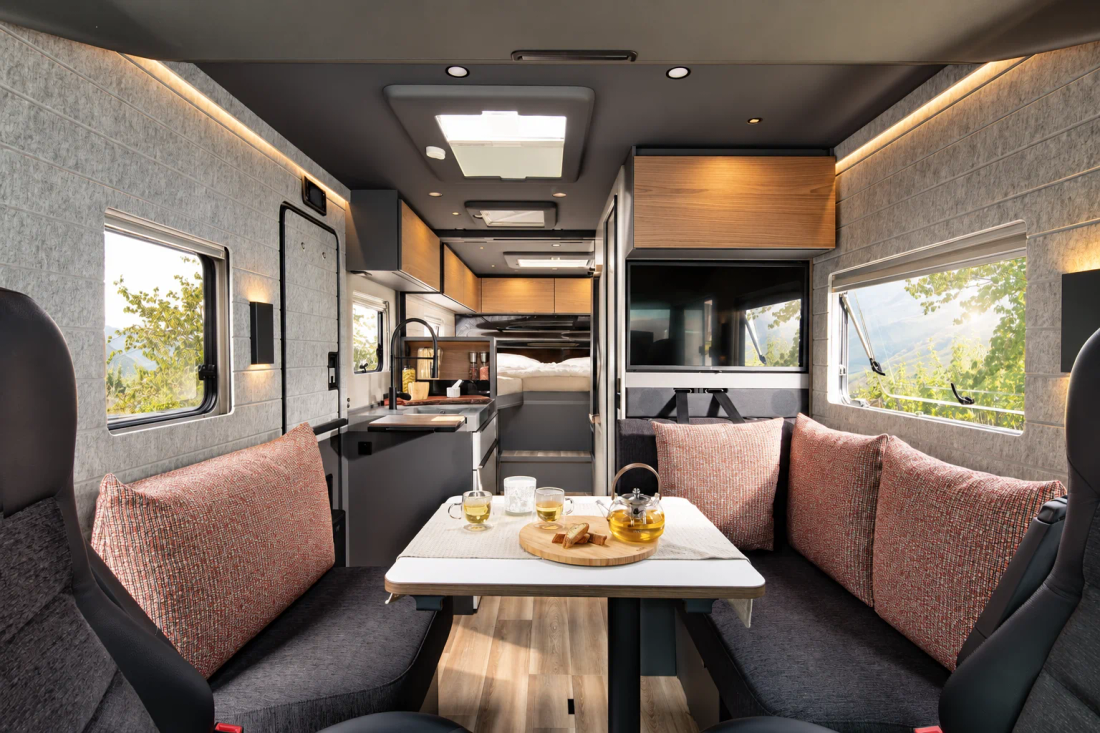 Salon de l'iSmove avec banquettes face-à-face, touches de bois et vue vers les lits arrière